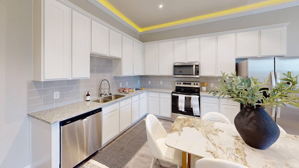 A kitchen with white cabinets and a marble table.