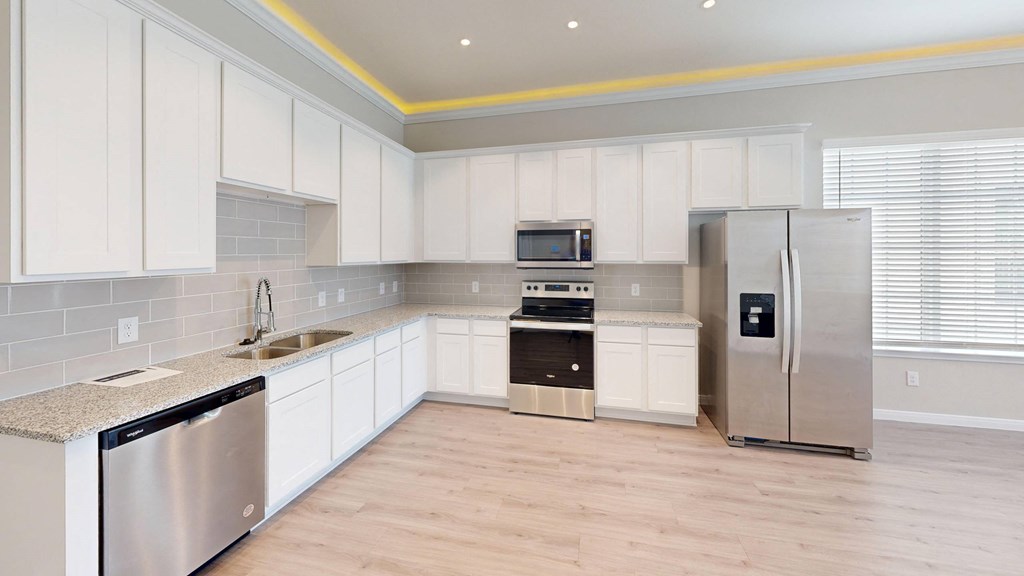 A kitchen with white cabinets and a stainless steel refrigerator.
