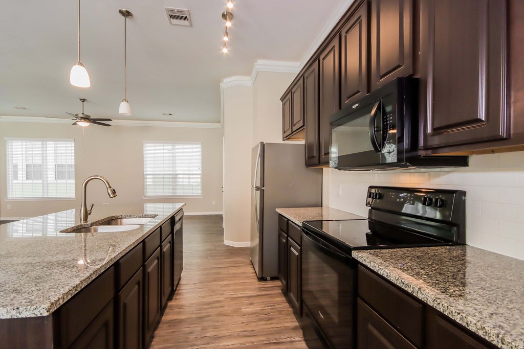 A kitchen with dark brown cabinets and granite countertops.