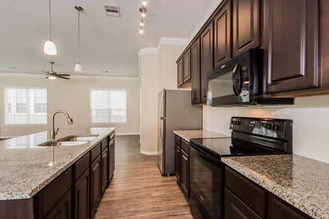 A kitchen with dark brown cabinets and granite countertops.