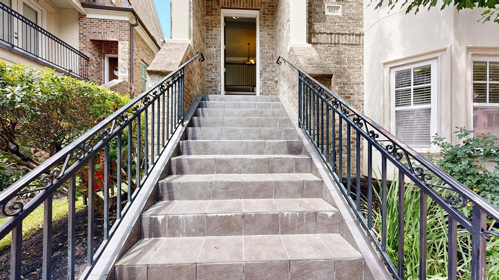A set of stairs with a metal railing lead to a doorway.