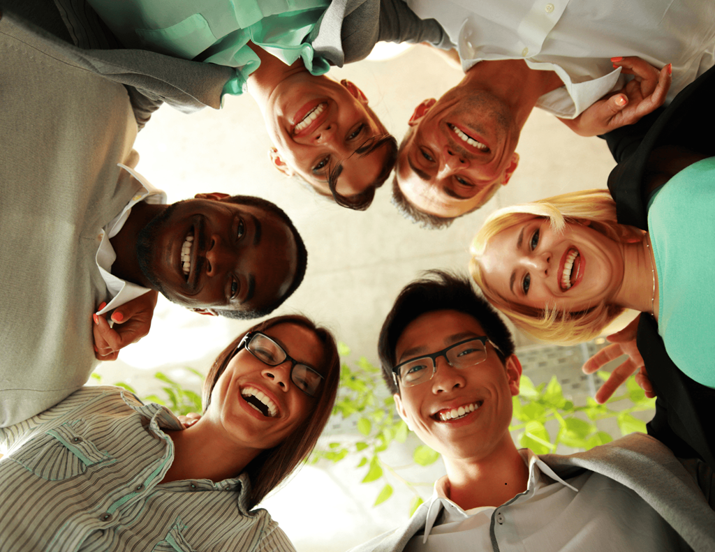 A group of people standing in a circle, smiling and looking up at the camera.