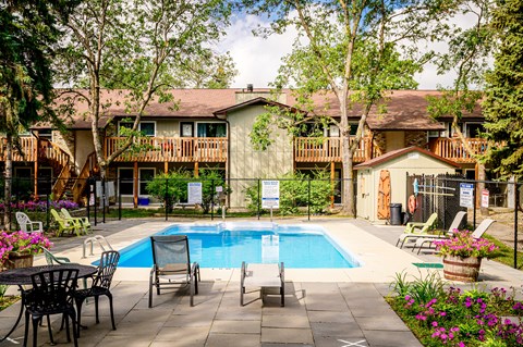 a swimming pool in front of a house with a pool table and chairs