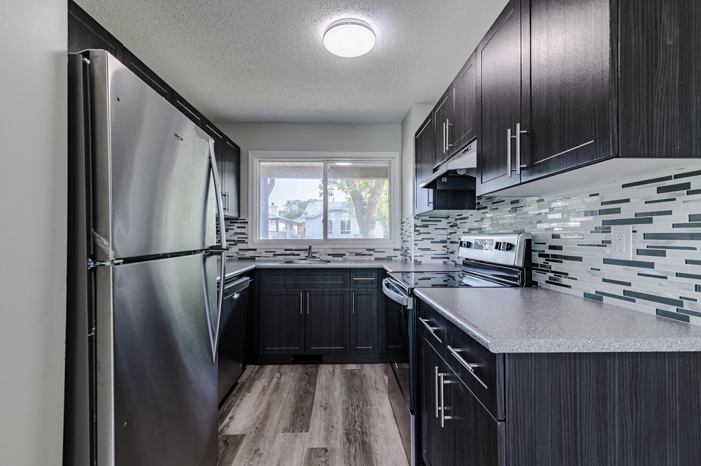 a kitchen with black cabinets and a stainless steel refrigerator