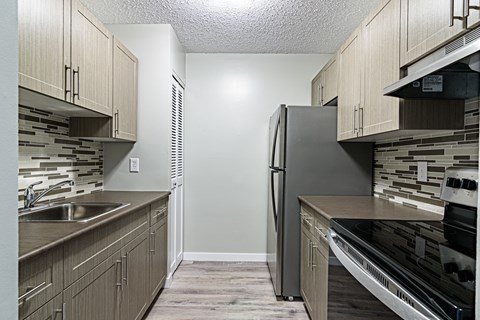 an empty kitchen with wooden cabinets and a stainless steel refrigerator