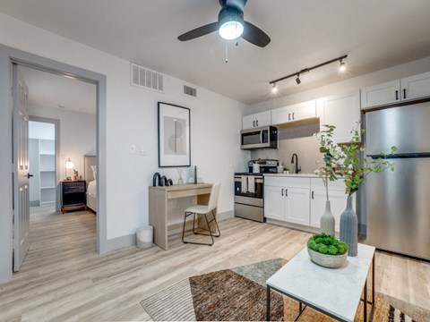 a living room with a kitchen and a ceiling fan