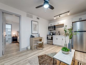 a living room with a kitchen and a ceiling fan
