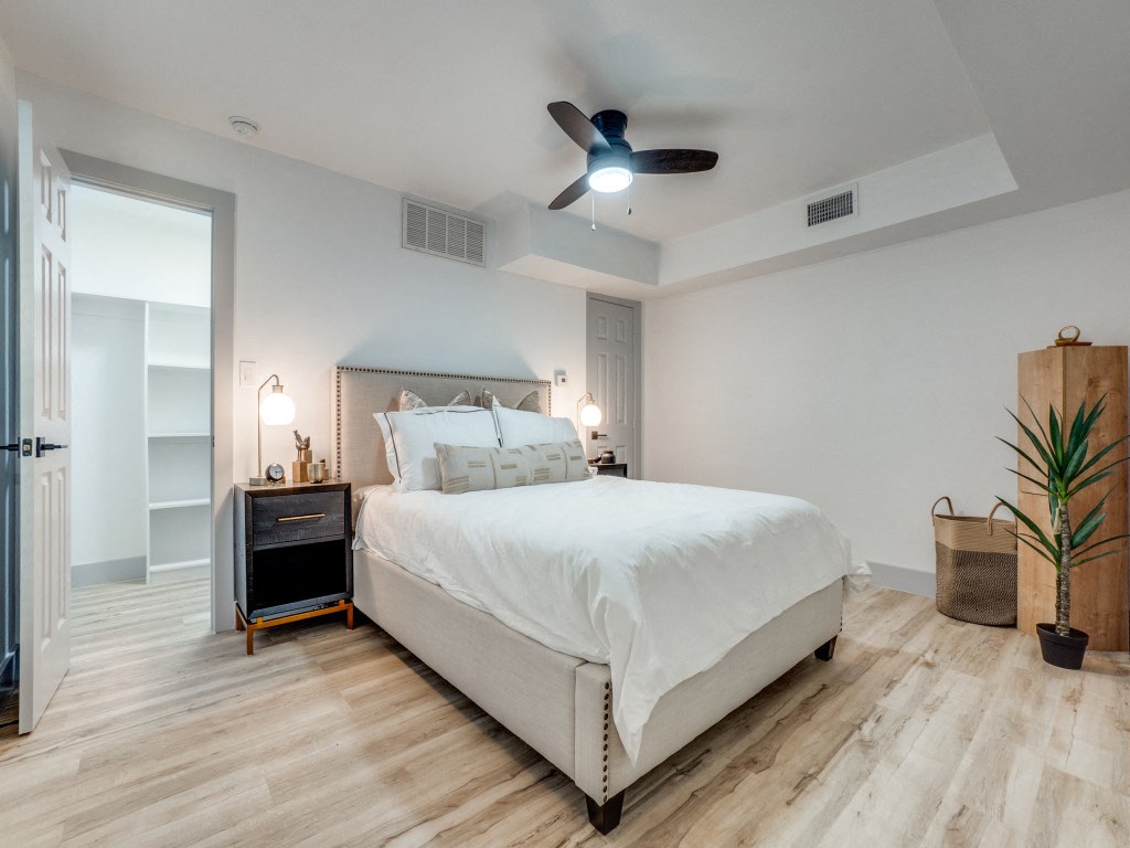 a white bedroom with a bed and a ceiling fan