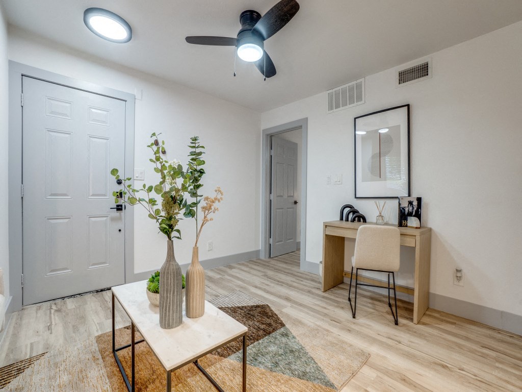 the living room and dining room of an apartment with a table and a desk