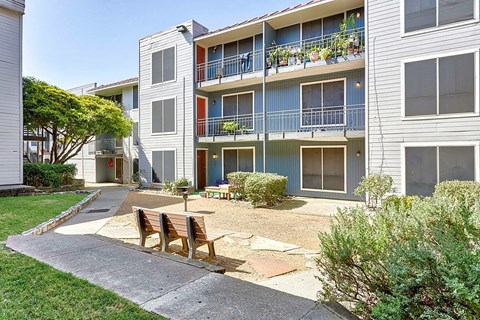 a patio in front of an apartment building with a table and chairs