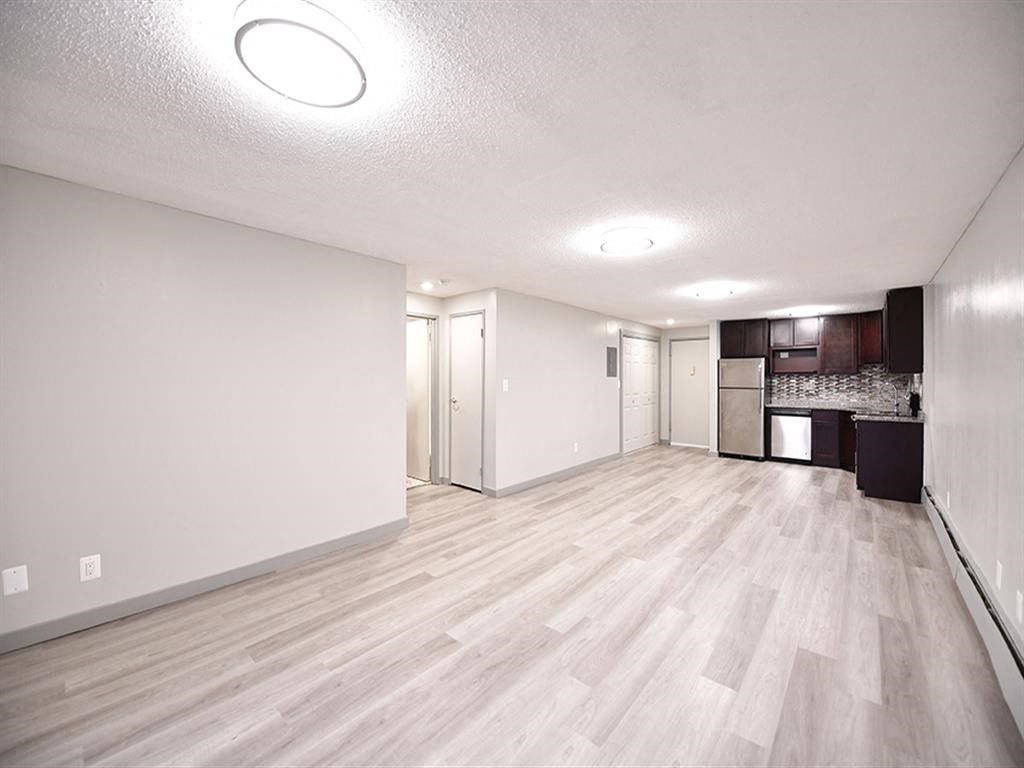 an empty living room and kitchen with wood flooring