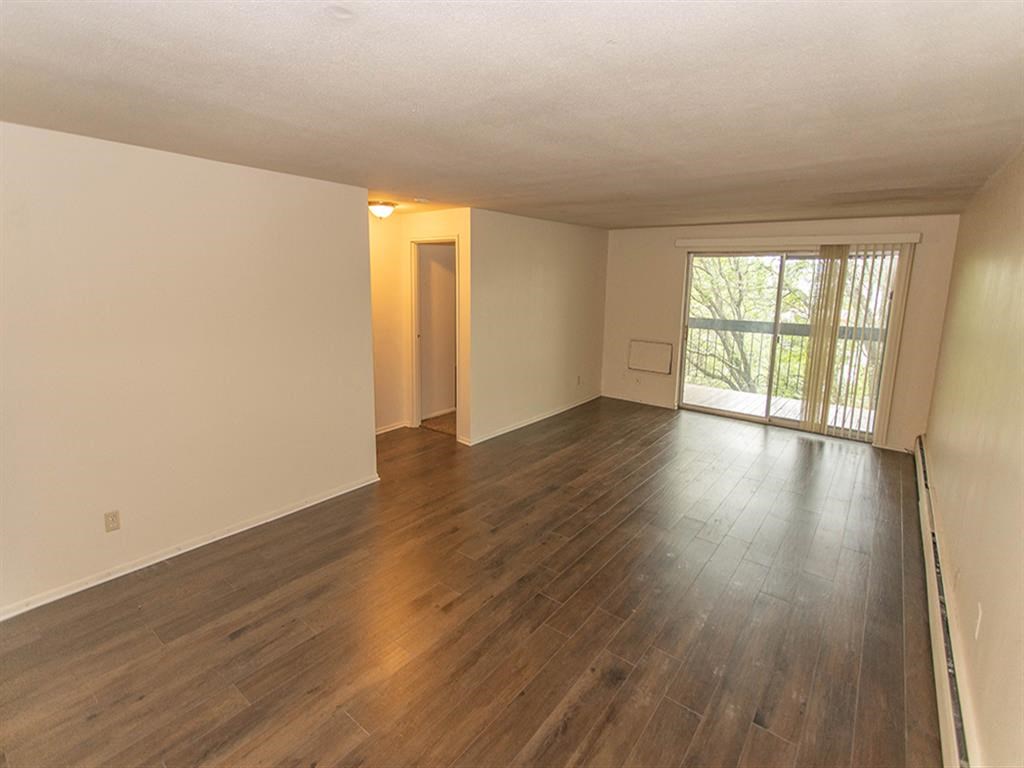 an empty living room with a hard wood floor and a window