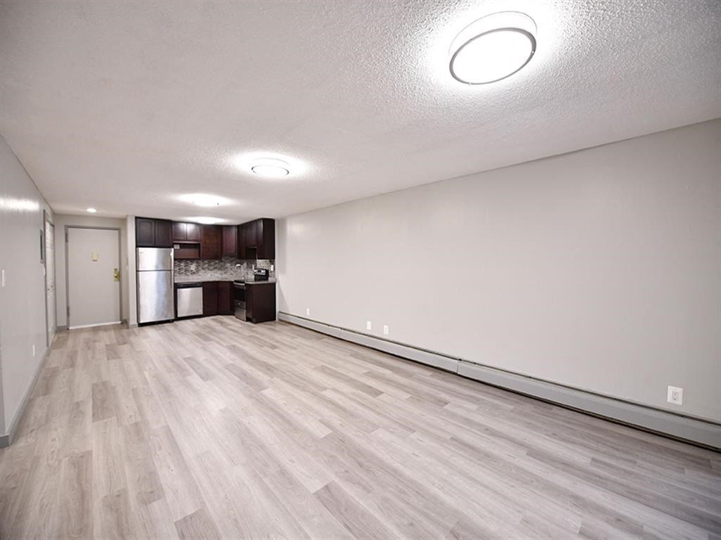 an empty living room and kitchen with wood flooring