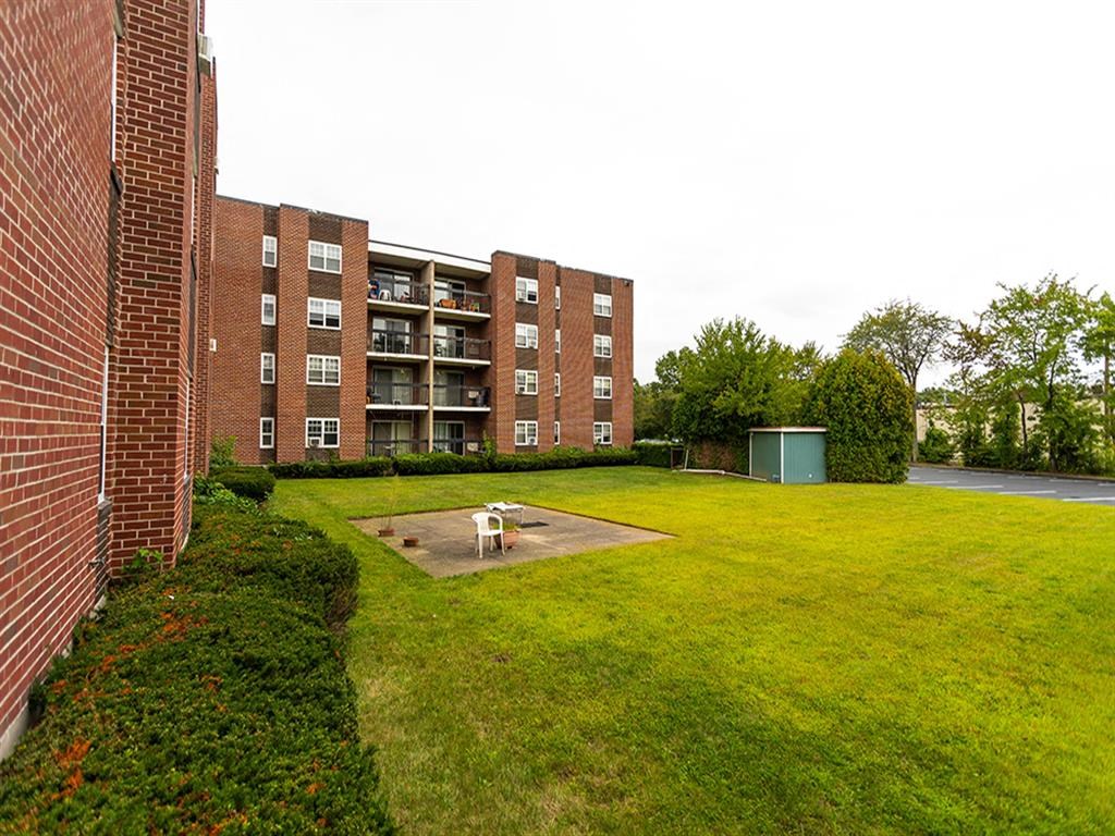 a dog sitting in the grass in front of an apartment building