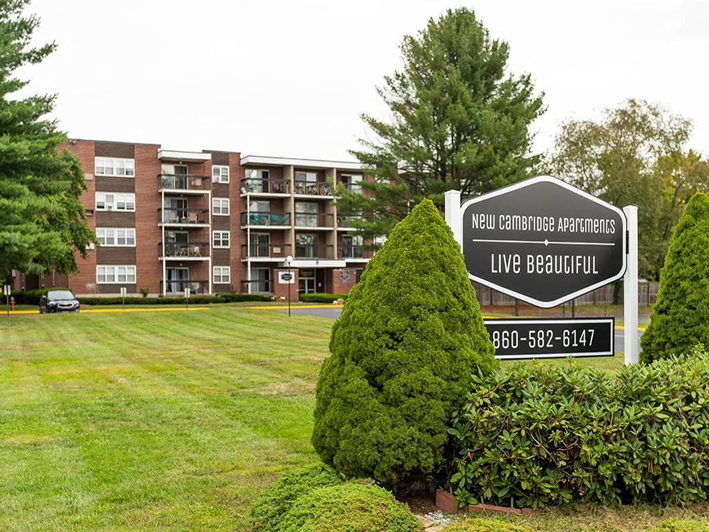 an apartment building with a sign in front of a lawn