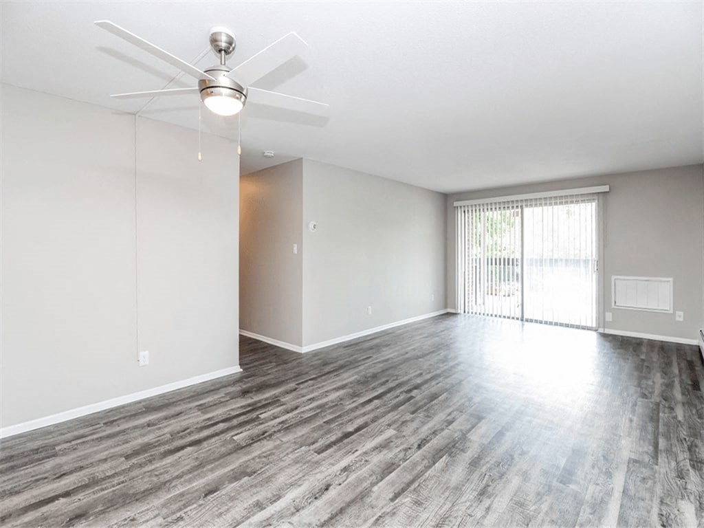 an empty living room with a ceiling fan and a window