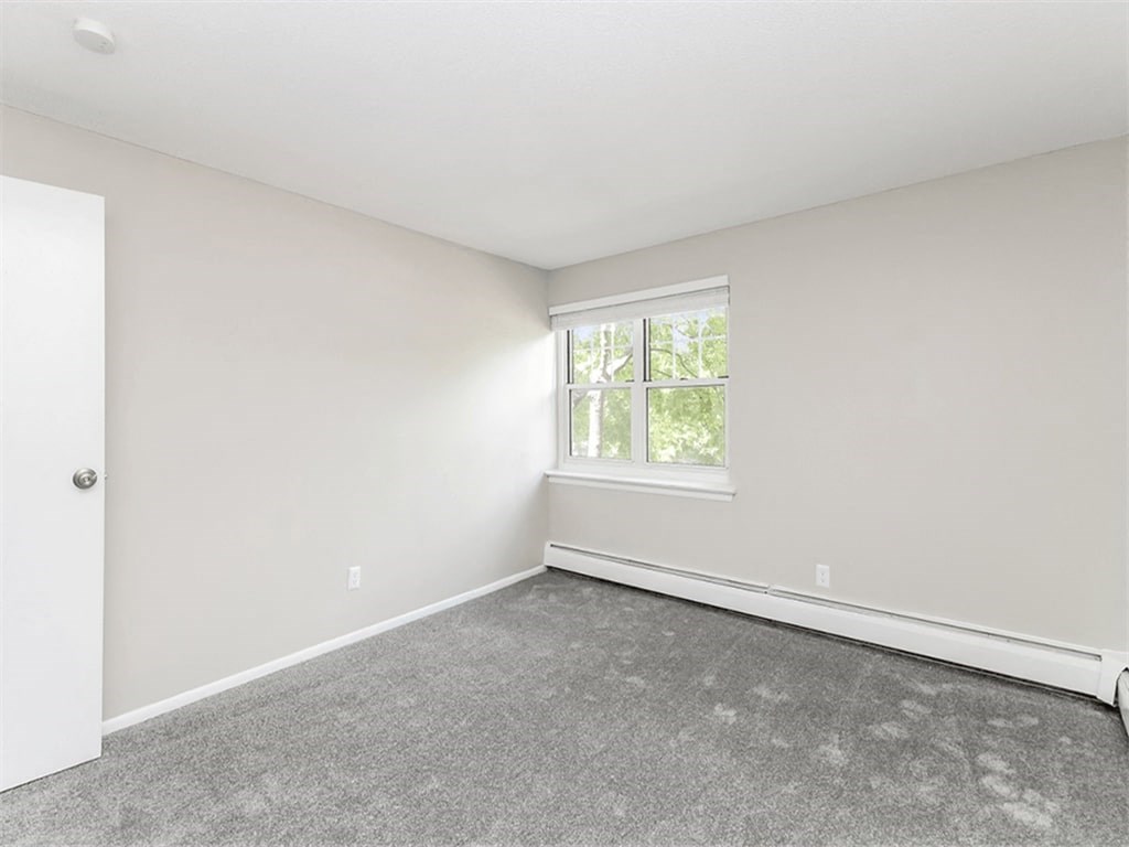 an empty living room with a window and carpet