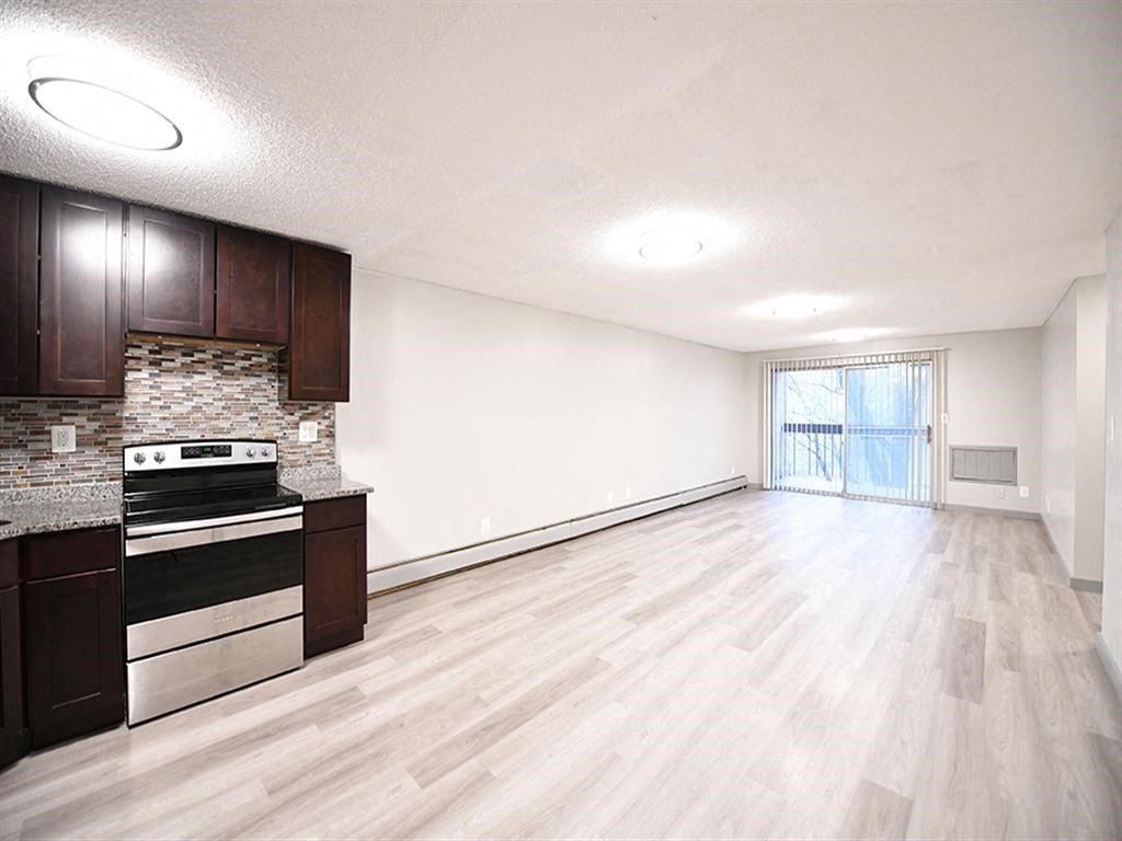 an empty living room and kitchen with wood flooring