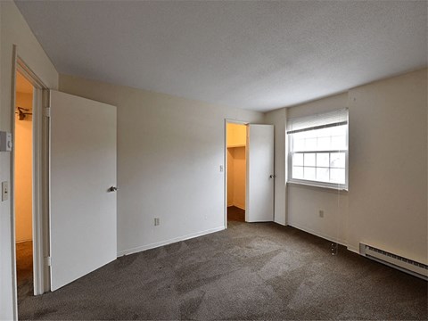the living room of an apartment with carpet and a window