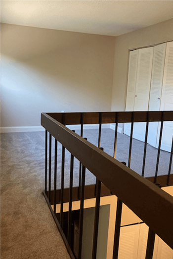 View of loft with grey carpet and wood railings at Silvertree Apartments - Photo Gallery 17