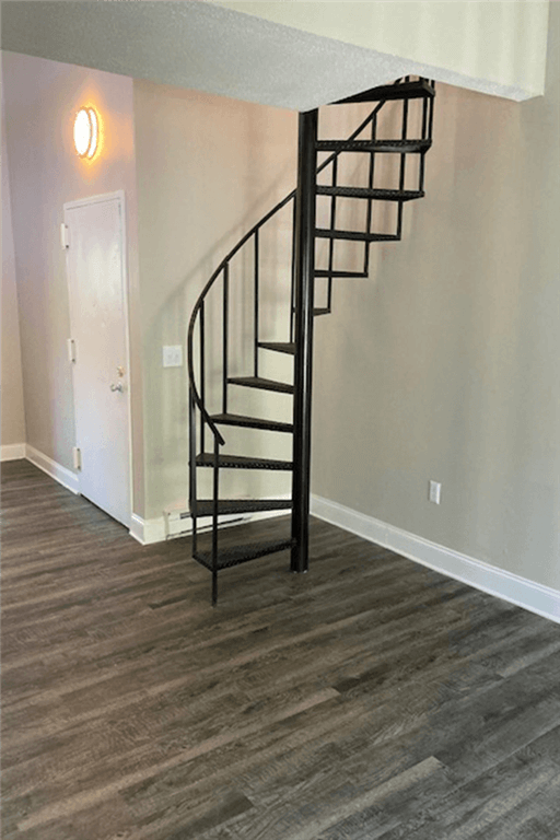View of spiral staircase at Silvertree Apartments showing sand wood plank-style flooring and light tan walls