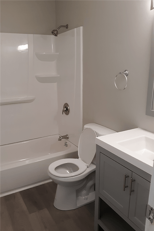 View of renovated bathroom showing soaking tub, toilet, and sink with grey cabinets