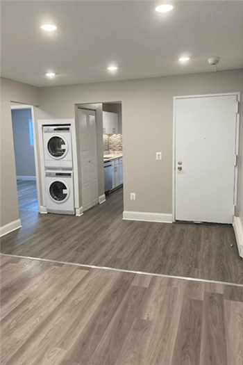 View of Renovated Apartment at Silvertree Apartments showing grey plank-style flooring and built-in washer and drying in unit. - Photo Gallery 14