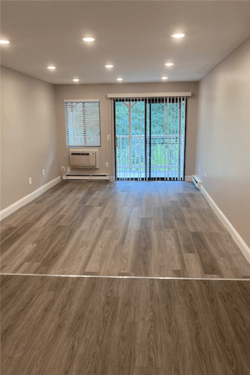 an empty living room with wood flooring and a window