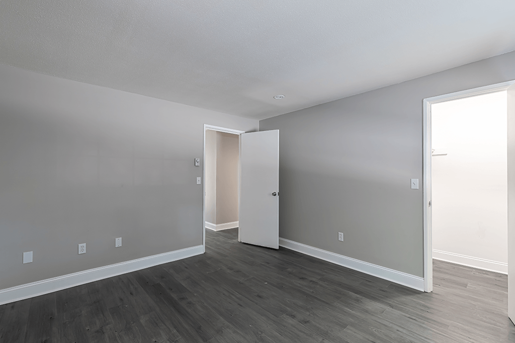 an empty living room with wood floors and a white door