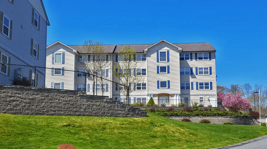 a large apartment building on a sunny day with a green lawn