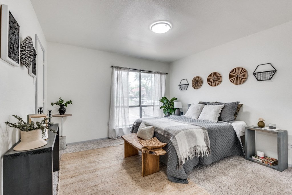 a bedroom with a bed and a dresser in front of a window