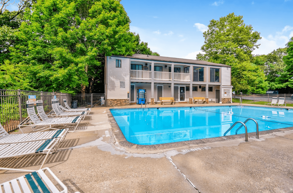 a swimming pool with chairs and a house in the background