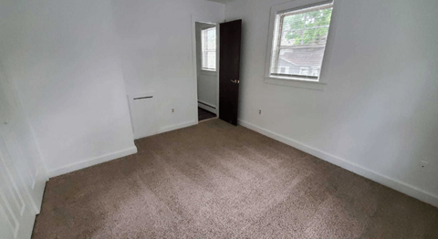 a room with a carpeted floor and a window and a door