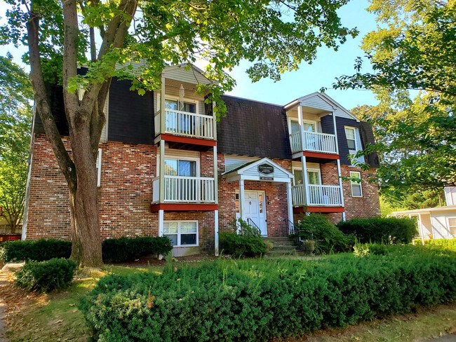 a brick apartment building with trees and bushes in front of it