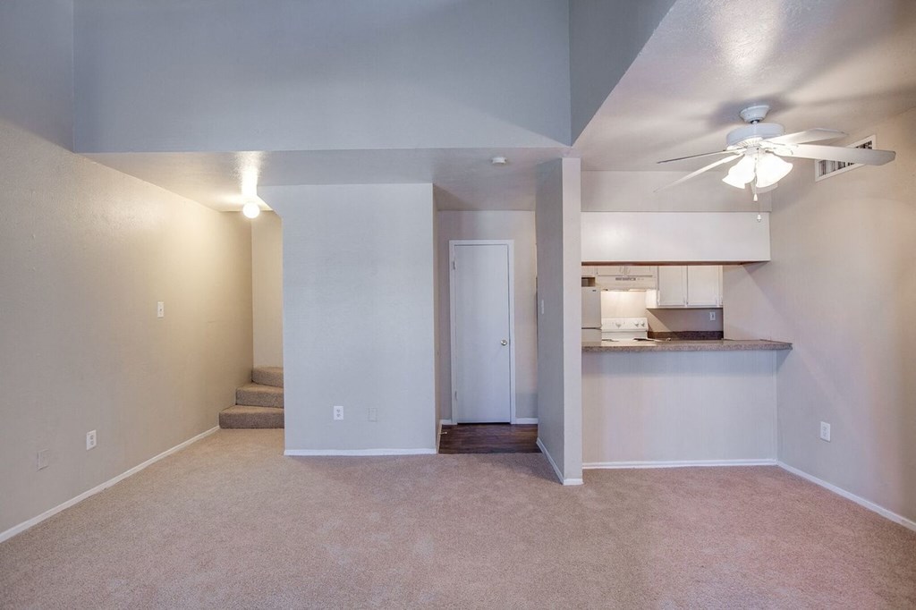 an empty living room and kitchen with a ceiling fan
