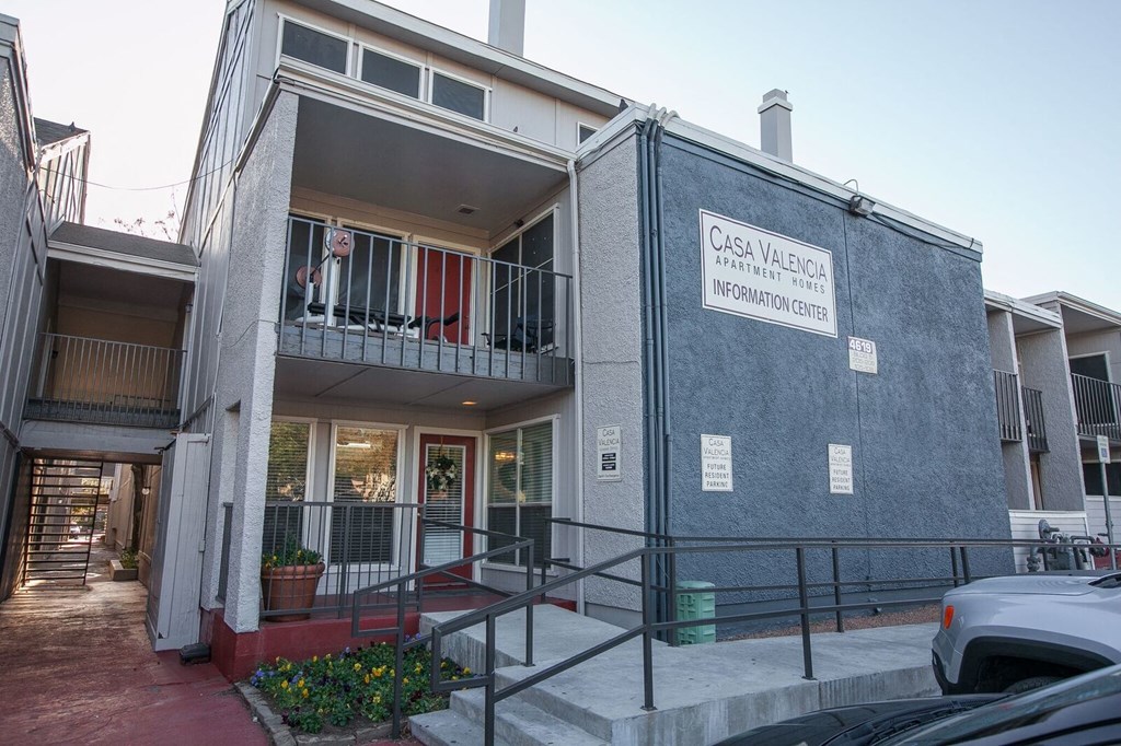 the front of a building with stairs and a sign