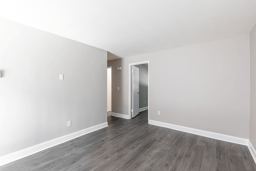 an empty room with white walls and wood floors