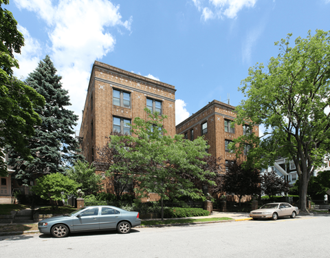 the facade of a brick building with cars parked in front of it