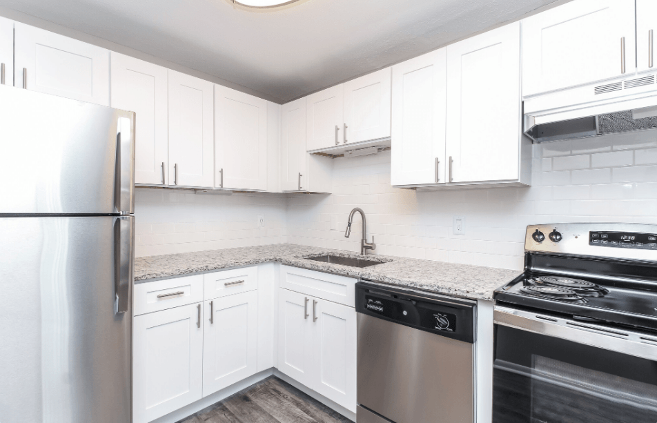 an empty kitchen with white cabinets and stainless steel appliances