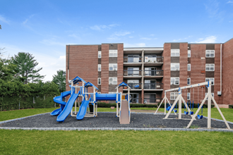 a playground in front of a building with slides and swings