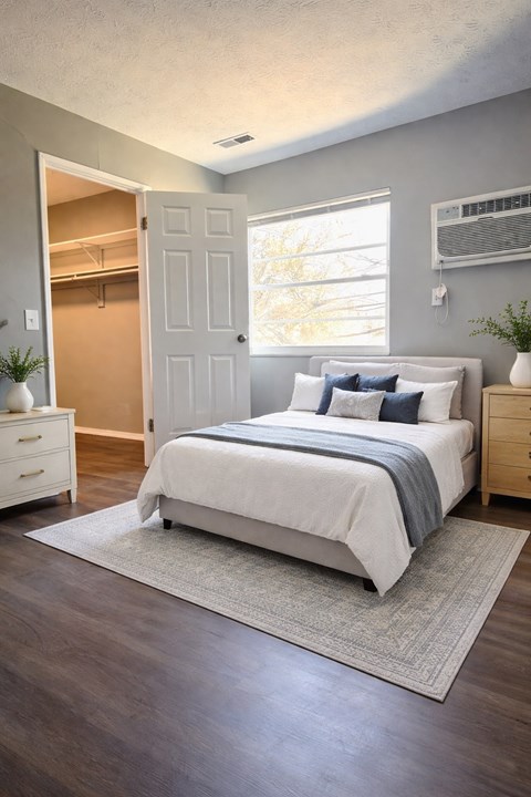 A bedroom with a bed, nightstand, and a window.