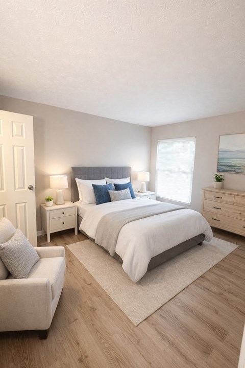 A bedroom with a large bed, a nightstand, a chair, and a rug.