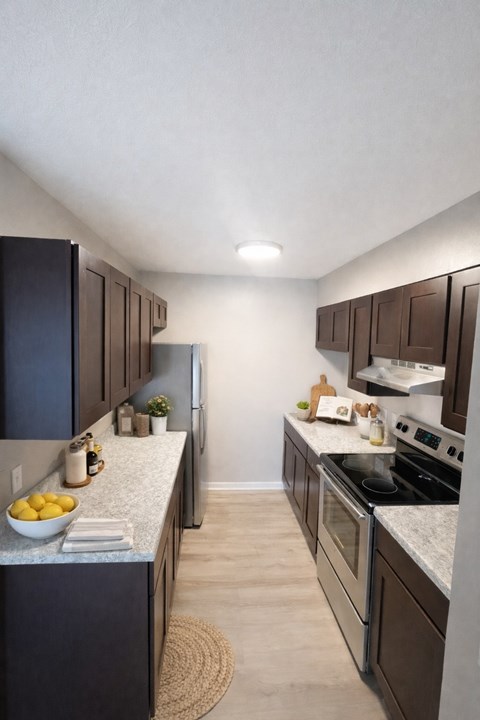 A kitchen with dark brown cabinets and a granite countertop.