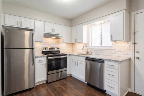 A kitchen with white cabinets and a stainless steel refrigerator.