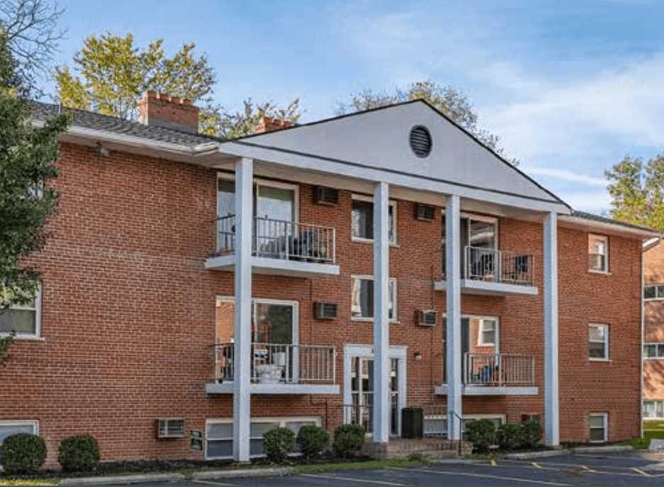 A red brick building with a white roof and a balcony on the second floor.