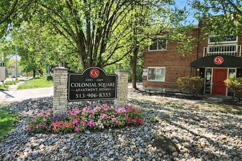 A sign for Colonial Square Apartment Homes is in front of a brick building.