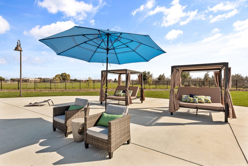 a patio with wicker furniture and a large blue umbrella