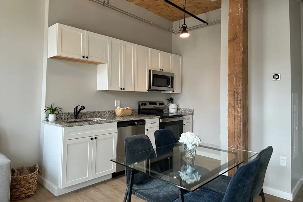 a kitchen with white cabinets and a glass table