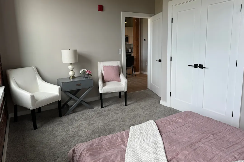 a bedroom with a bed and two chairs and a table