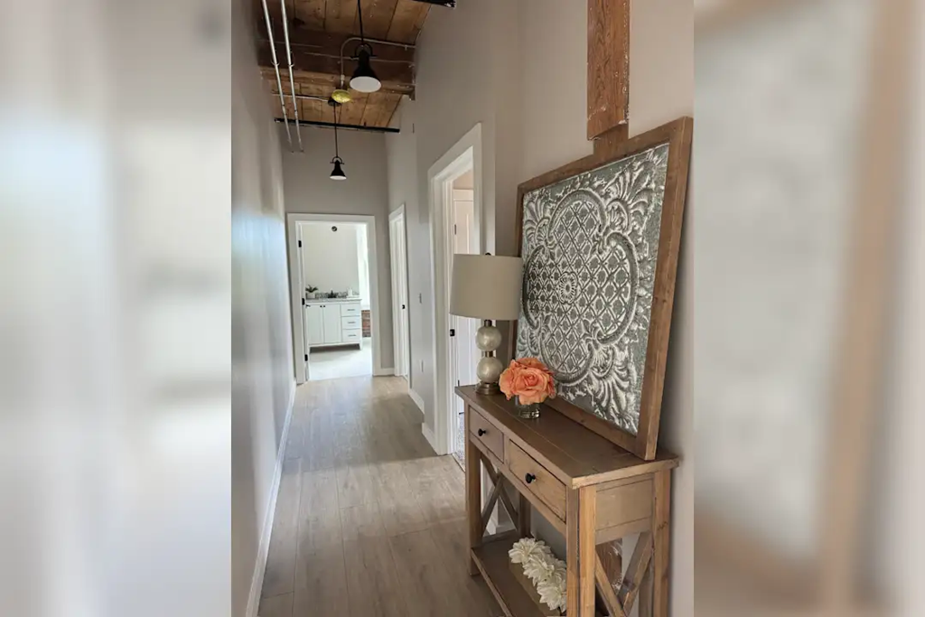 a hallway with a painting and a table with a lamp